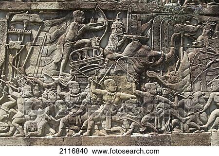 Stock Image - Cambodia, Siem Reap, Angkor Thom, Angkor Archaeological Park, Story carved onto exterior of building.. Fotosearch