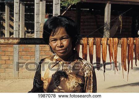 Stock Photo - Cambodia, Siem Reap, Woman Drying Snakes On Stick To Sell.. Fotosearch