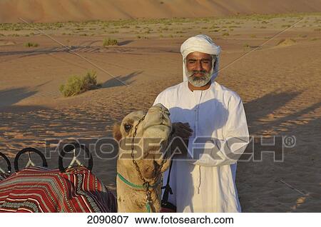 Stock Photo - Camel And Guide In Liwa Desert Dunes, Abu Dhabi. Fotosearch