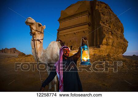 Picture - Camel and rider with Madain Saleh in the background; Madain Saleh, Saudi Arabia. Fotosearch