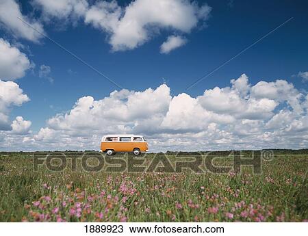 Stock Image - Campervan Going Down Road In Front Of Heather In Flower. Fotosearch