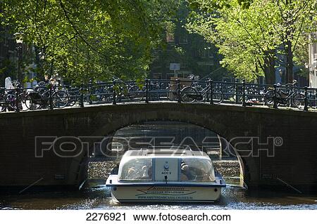 Canal cruise boat going under bridge; Amsterdam, Holland View Large Photo Image Stock Image - Canal cruise boat going under bridge; Amsterdam, Holland. Fotosearch
