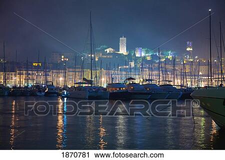 Stock Image - Cannes, Provence, France; Buildings Illuminated On Shore And The Harbor At Night. Fotosearch