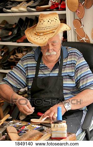 Stock Image - Capri, Italy; Senior Male Craftsman Making Leather Sandals. Fotosearch