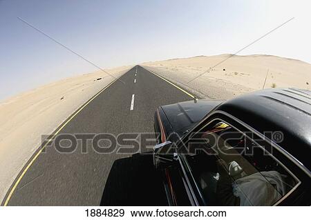 Stock Photo - Car Driving Along Remote Desert Road. Fotosearch
