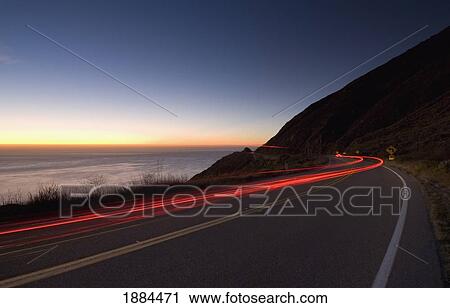 Stock Image - Car Going Down The Big Sur Coastal Road At Dusk. Fotosearch