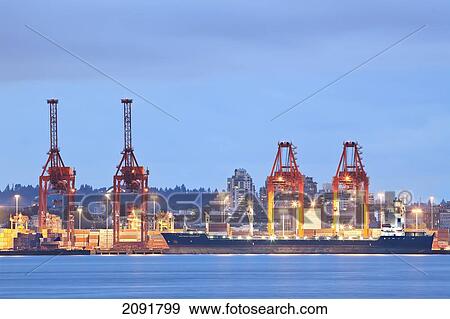 Stock Photo - Cargo Ship Loading At Dusk In Port Of Vancouver; Vancouver, British Columbia, Canada. Fotosearch