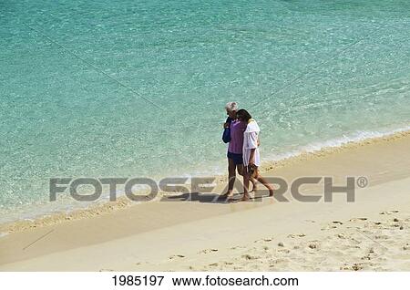 Stock Photo - Caribbean, Barbados, Senior Couple Walking Along Beach, Clear Turquoise Ocean Water.. Fotosearch