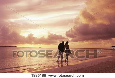 Caribbean, Couple wading in calm ocean along beach at sunset; Antiqua View Large Photo Image Stock Photo - Caribbean, Couple wading in calm ocean along beach at sunset; Antiqua. Fotosearch