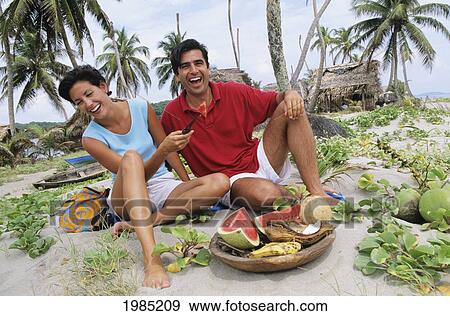 Caribbean, Honduras, The Bay Islands, Couple Eating Tropical Fruit On Sandy Seashore. View Large Photo Image Stock Photo - Caribbean, Honduras, The Bay Islands, Couple Eating Tropical Fruit On Sandy Seashore.. Fotosearch