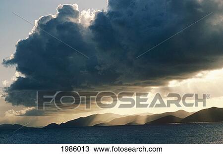 Caribbean, Puffy Storm Clouds At Sunset Over Ocean, Sun Rays Over Hills In Distance. View Large Photo Image Stock Image - Caribbean, Puffy Storm Clouds At Sunset Over Ocean, Sun Rays Over Hills In Distance.. Fotosearch