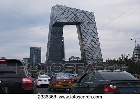 Cars In Traffic On The Road With A Uniquely Shaped Modern Building In The Background; Beijing, China View Large Photo Image Stock Photo - Cars In Traffic On The Road With A Uniquely Shaped Modern Building In The Background; Beijing, China. Fotosearch