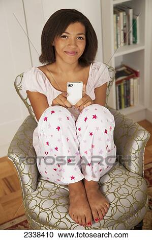 Stock Image - Casually Dressed Woman At Home Using Her Smart Phone; San Francisco, California, Usa. Fotosearch