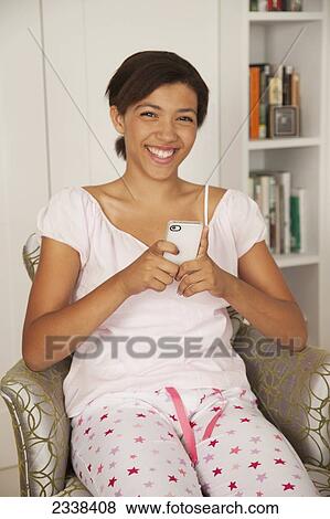 Stock Photo - Casually Dressed Woman At Home Using Her Smart Phone; San Francisco, California, Usa. Fotosearch