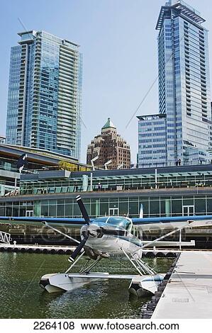 Stock Photo - Cessna Seaplane Moored At Vancouver Harbour Flight Centre With Convention Centre Backdrop; Vancouver British Columbia Canada. Fotosearch