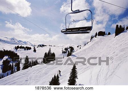 Stock Photograph - Chairlift Over Snow Covered Mountain With Pine Trees. Fotosearch