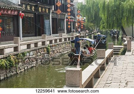 Stock Image - Channels the boatmen drive their boats as Venetia, beautiful traditional Chinese architecure as background; ZhouZhuang, Shanghai, China. Fotosearch
