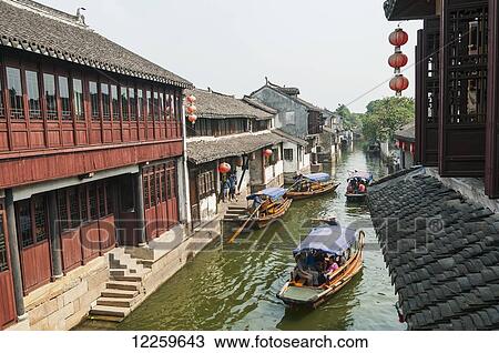 Stock Image - Channels the boatmen drive their boats as Venetia, beautiful traditional Chinese architecure as background; ZhouZhuang, Shanghai, China. Fotosearch