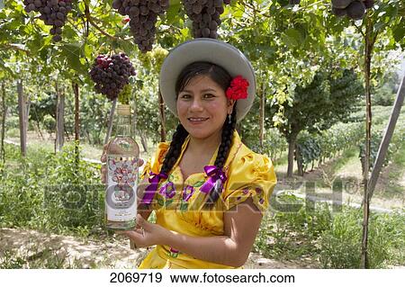 Stock Photo - Chapaca Holding A Bottle Of Singani In A Vineyard Of Calamuchita, Tarija, Bolivia. Fotosearch