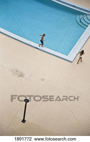 Stock Image - Children (10-11) Walking Around Swimming Pool, Elevated View. Fotosearch