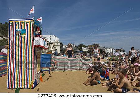 Stock Photograph - Children and parents watching a Punch and Judy puppet show at Viking Bay; Broadstairs, Kent, England. Fotosearch