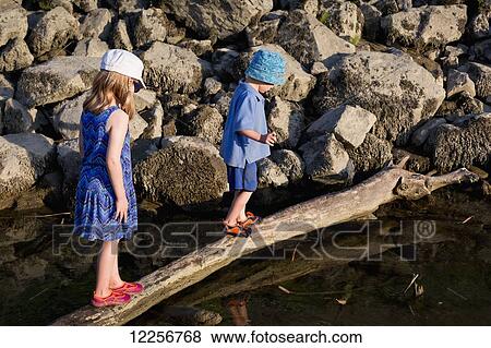 Children walking on a log over the water; Chilliwack, British Columbia, Canada View Large Photo Image Stock Photo - Children walking on a log over the water; Chilliwack, British Columbia, Canada . Fotosearch