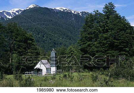 Stock Image - Chile, Mountains in background; Andes Mountains, Small white church in grassy area surrounded by forest. Fotosearch