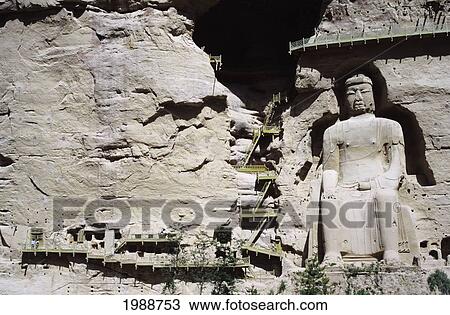 Stock Image - China, Bingling Si Caves, Large Statue Carved Into Mountainside, Stairs Leading In And Around Caves. Fotosearch