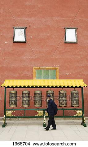Picture - China, Chengde, Putuo Zongcheng Temple, Old Man Walking By Prayer Wheels.. Fotosearch