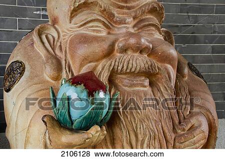Stock Photo - China, Guangdong, Dragon Kiln Nanfeng pottery; Foshan, Statue of smiling man holding nut. Fotosearch