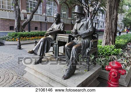 Stock Photograph - China, Guangdong, Shamian Island; Guangzhou, Statues on bench. Fotosearch