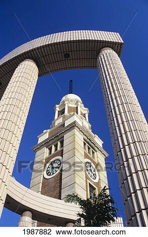 Stock Image - China, Hong Kong, Low angle view of Old Kcr Station Clock Tower through modern structure; Kowloon. Fotosearch