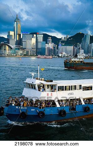 Stock Photo - China, Kowloon; Hong Kong, Hong Kong Island skyline in background view from Tsim Sha Tsui, Boats in Victoria Harbor at dusk. Fotosearch