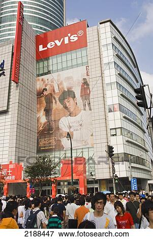 Stock Photo - China. Shanghai. Nanging Donglu Shopping Area. Crowd Of Pedestrian In Front Of A High Rising Shopping Mall With Advertising Poster. Fotosearch