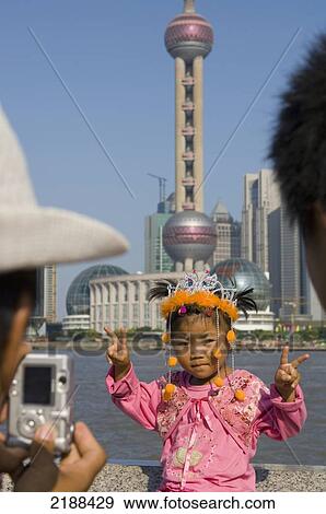 Stock Photo - China. Shanghai. The Bund (Waitan). Young Child In Pink Clothes Pausing For A Picture In Front Of Jinmao Tower And New Pudong Area. Fotosearch