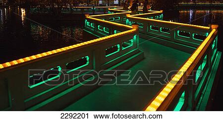 Stock Image - China, Xizang, Lhasa, Path going over pond illuminated with colorful lights. Fotosearch