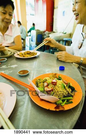 Stock Image - Chinese Women Eating Fried Oysters And Noodle Dishes. Fotosearch