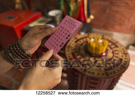 Stock Photo - Chinese young woman trying the traditional roll of fortune in a Buddhist temple; Shanzidou, Kinmen Island, Taiwan. Fotosearch