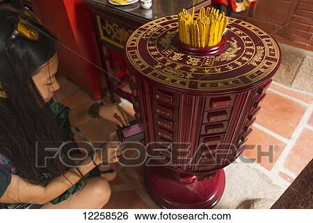 Chinese young woman trying the traditional roll of fortune in a Buddhist temple; Shanzidou, Kinmen Island, Taiwan View Large Photo Image Stock Photograph - Chinese young woman trying the traditional roll of fortune in a Buddhist temple; Shanzidou, Kinmen Island, Taiwan. Fotosearch
