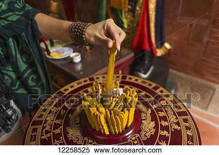 Stock Photography - Chinese young woman trying the traditional roll of fortune in a Buddhist temple; Shanzidou, Kinmen Island, Taiwan. Fotosearch