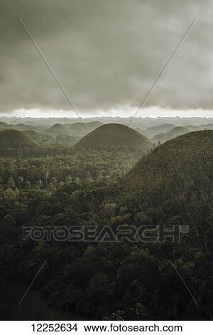 Picture - Chocolate hills landscape from Bohol Island, a big storm covers the sky making an interesting lighting effect; Carmen, Bohol Island, Philippines. Fotosearch