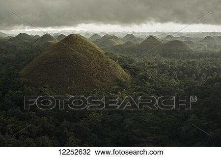 Stock Image - Chocolate hills landscape from Bohol Island, a big storm covers the sky making an interesting lighting effect; Carmen, Bohol Island, Philippines. Fotosearch