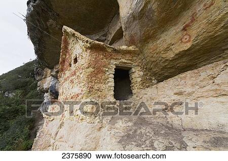 Stock Image - Chullpa (stone tomb chamber) of the Chachapoya culture with walls colored with red figures, nestled in the limestone cliffs of Cerro Carb. Fotosearch