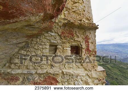 Stock Image - Chullpas (stone tomb chambers) of the Chachapoya culture nestled in the limestone cliffs of Cerro Carb. Fotosearch