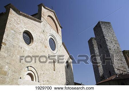 Stock Image - Church and two of the Towers of San Gimignano, a famous medieval hilltop town with old towers, in Tuscany. Italy. June.. Fotosearch