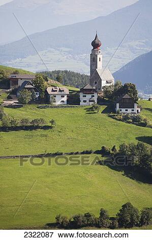 Stock Photo - Church with onion dome tower on meadow with mountains and valleys in background; Bolzano, Dolomites, Alto Adige, Italy. Fotosearch