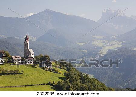 Stock Photography - Church with onion dome tower on meadow with mountains and valleys in background; Bolzano, Dolomites, Alto Adige, Italy. Fotosearch