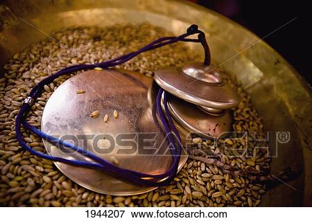 Stock Photo - Circular Bronze Items In A Bowl Full Of Grains Of Rice; Leh Ladakh India. Fotosearch