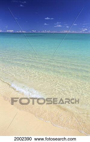 Stock Image - Clear Wave Rolling On Shore, Turquoise Water, Blue Skies, Small White Clouds Horizon. Fotosearch