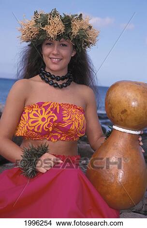 Picture - Close-Up Hawaiian Woman In Hula Attire With Haku Holding Wooden Vase Beach Background. Fotosearch